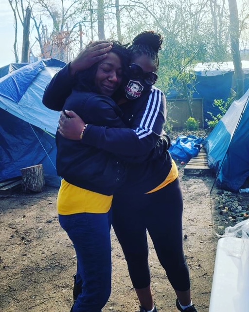 Two volunteers hugging during Feeding the Homeless Tent City event.