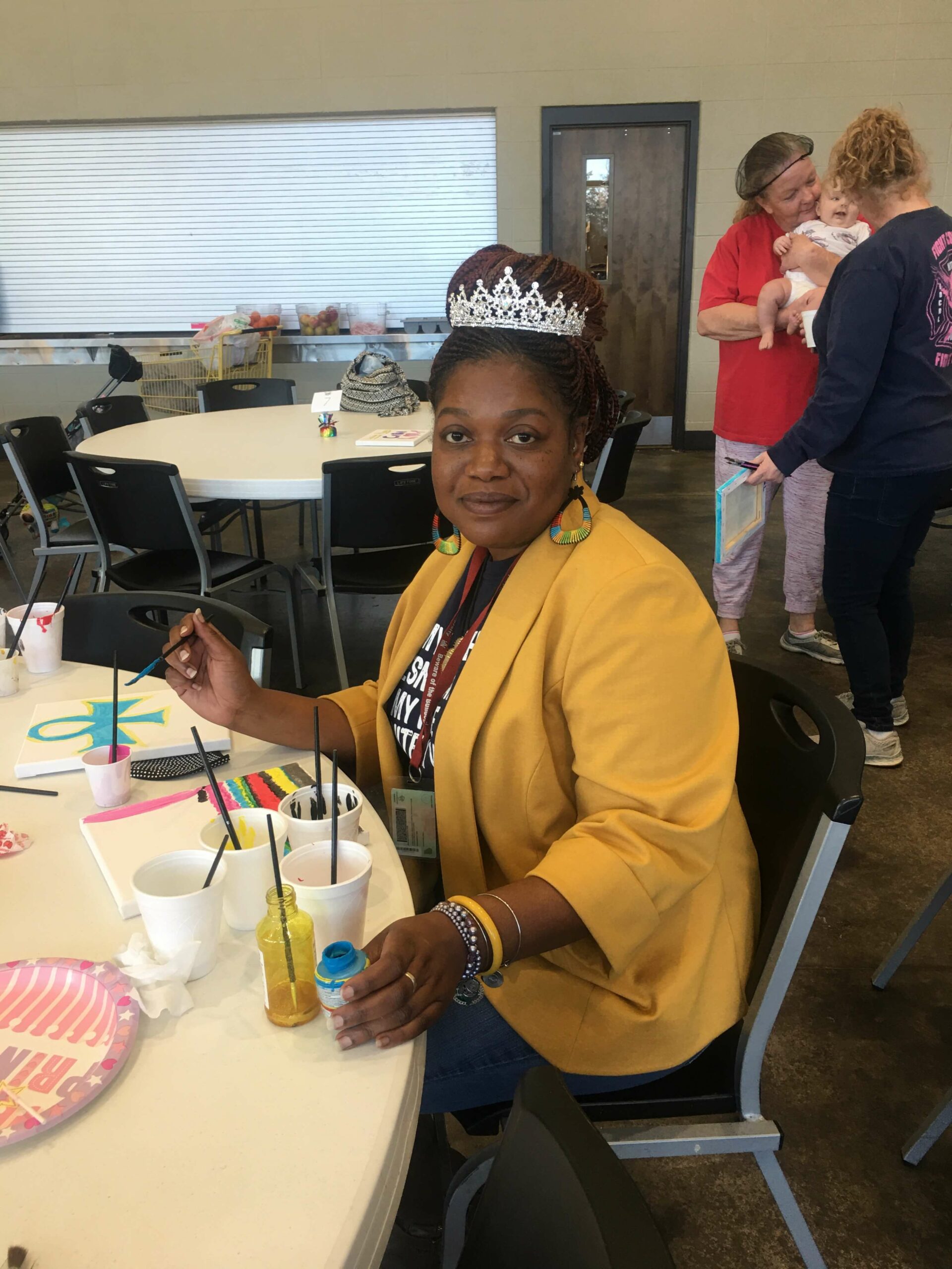 A picture of a volunteer smiling and painting at a Paint Party event.