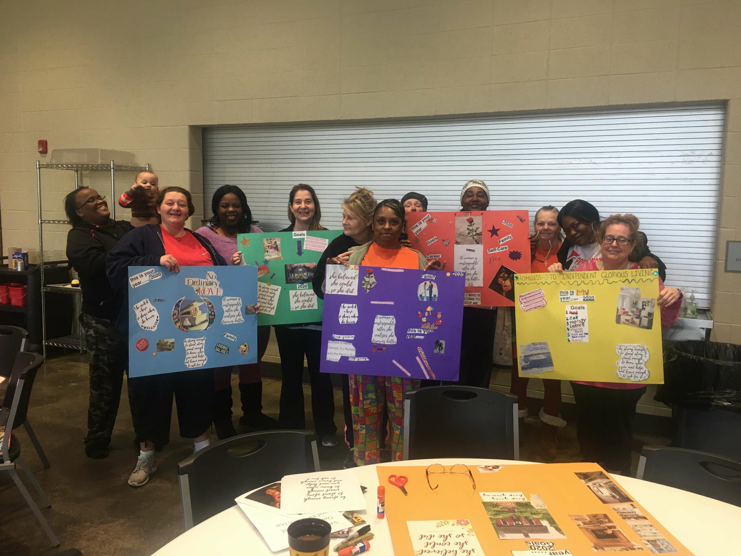 A group photo of volunteers smiling and holding their vision boards.